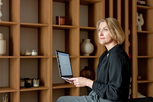 Woman in Black Top Holding a Laptop