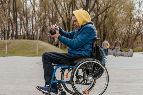 Free Man in a wheelchair capturing photos with a camera in an outdoor setting, Dnipro, Ukraine. Stock Photo