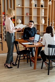 Three professionals engage in a meeting in a modern office setting, focusing on teamwork and collaboration.