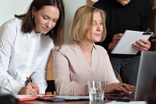 Free Three colleagues collaborating in a well-lit office space, focused on work tasks. Stock Photo