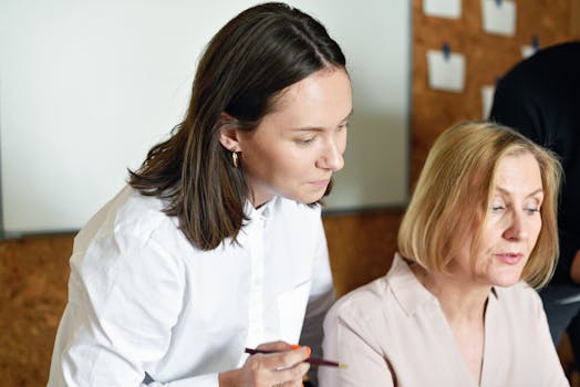 Two professional women discussing work collaboratively in a modern office environment.