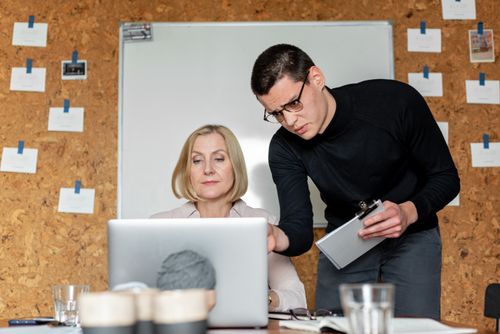 Free Office teamwork discussing plans with laptop and clipboard. Stock Photo