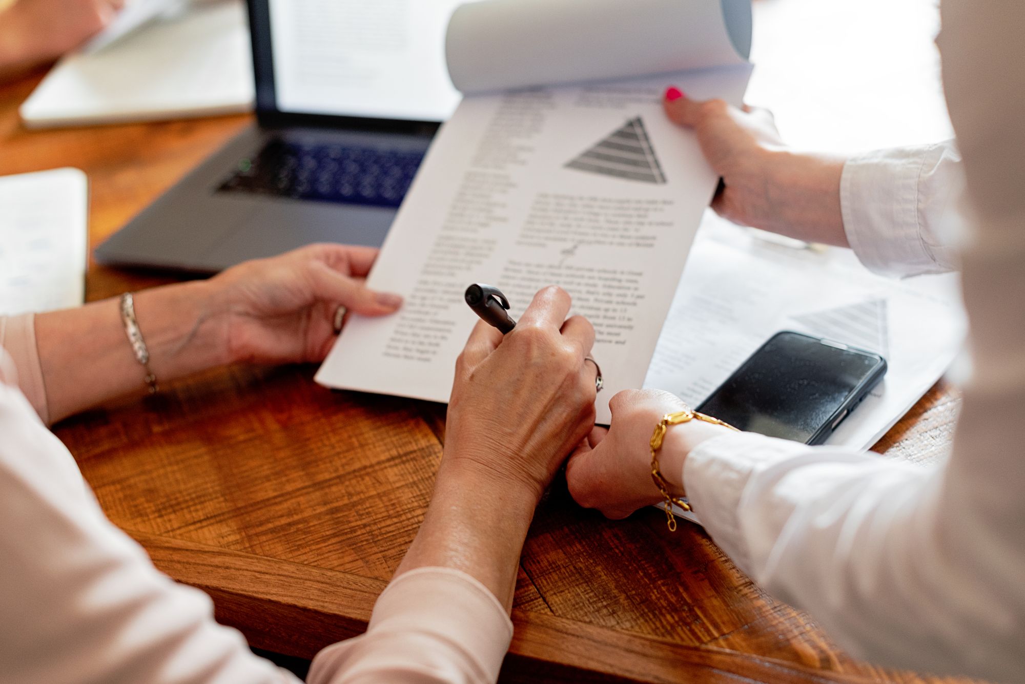 Two people reviewing printed documents together at a wooden table