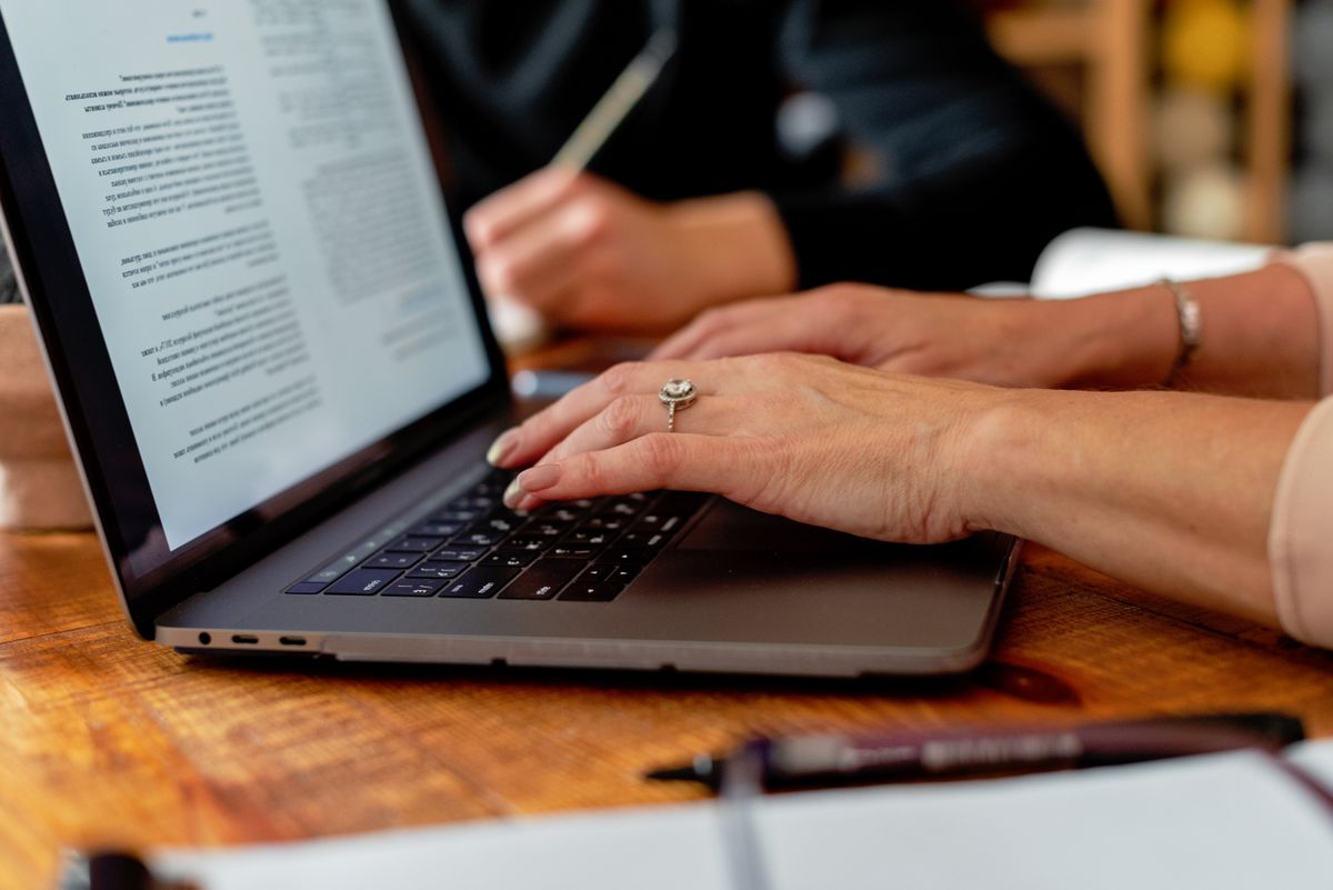 Hands typing on a laptop with a document open on screen