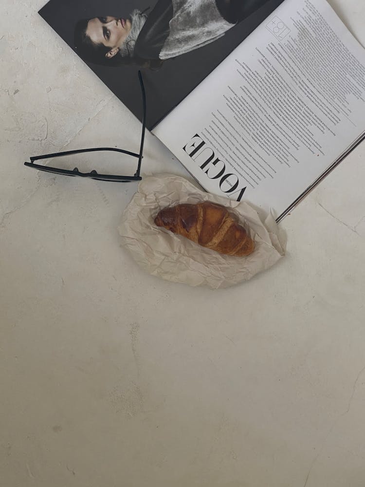 Croissant And Magazine On White Table