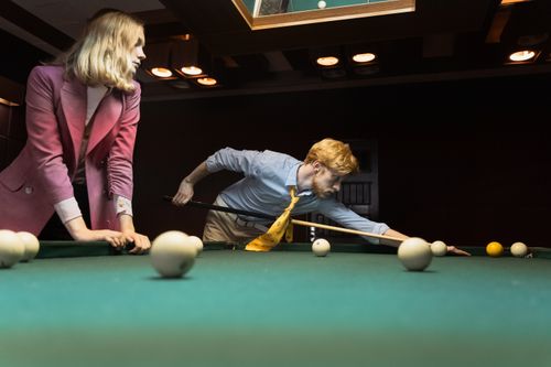 Free Two young adults playing billiards in a dimly lit room, focused on the game. Stock Photo
