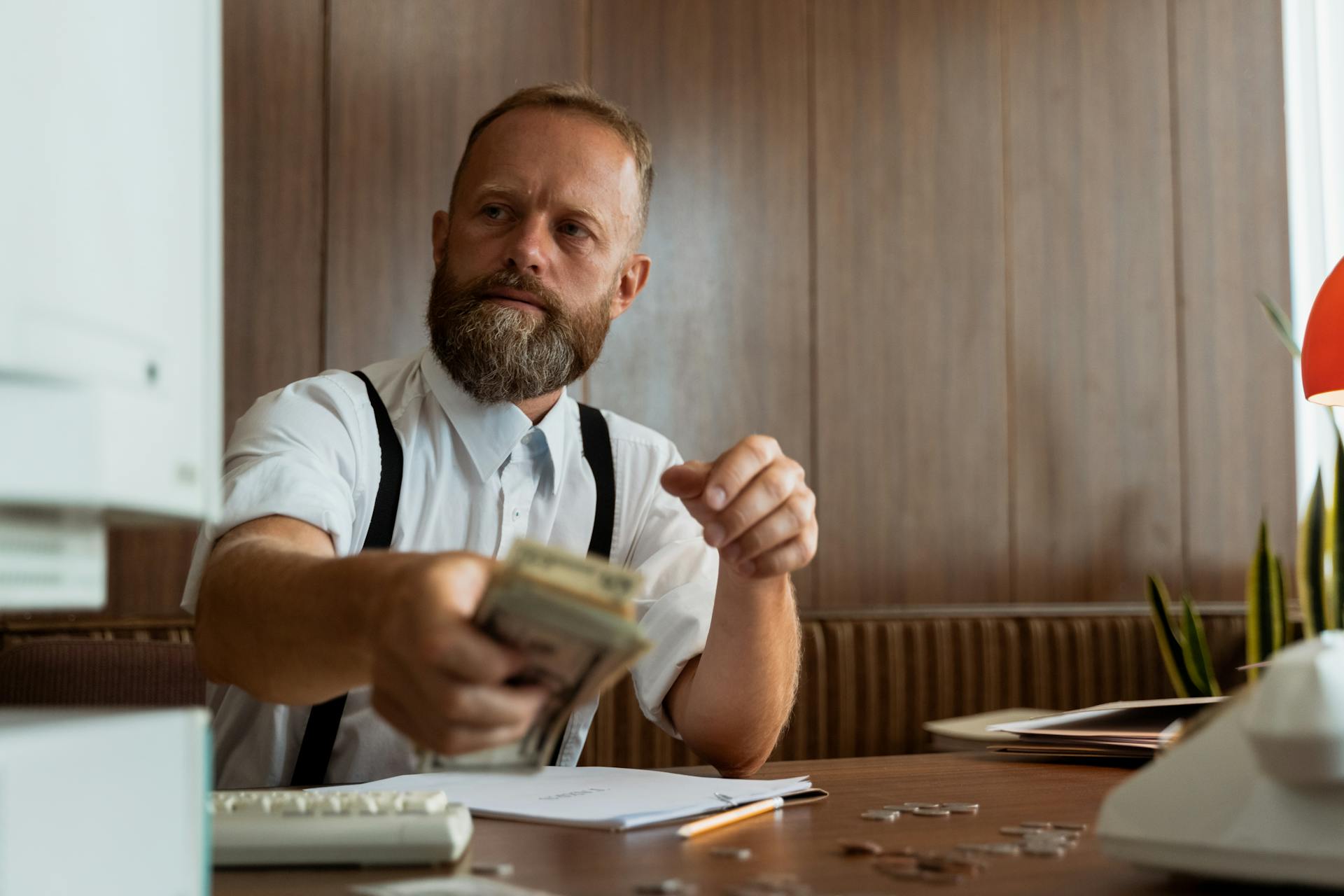 Businessman in a corporate office handling a stack of cash at his desk.