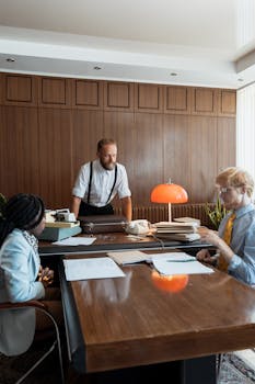 Business professionals in vintage office setting discussing work with typewriter and documents.