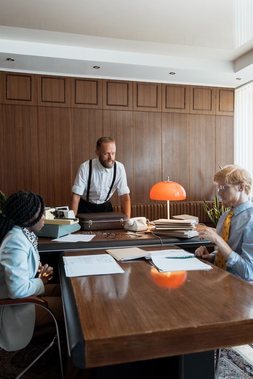 Free Business professionals in vintage office setting discussing work with typewriter and documents. Stock Photo