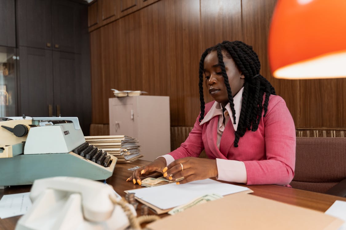 Free A Woman Counting Cash at her Work Desk Stock Photo