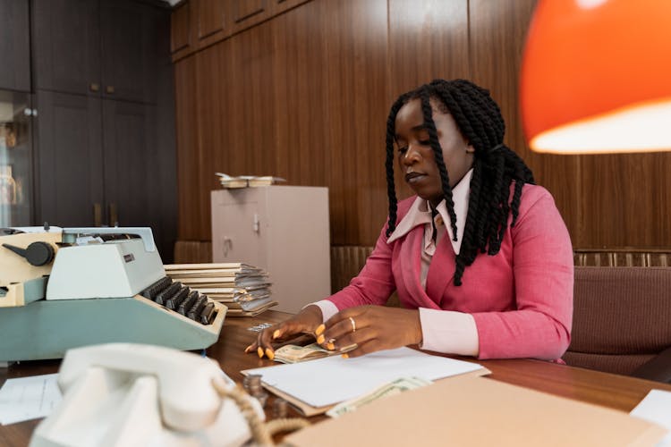 A Woman Counting Cash At Her Work Desk