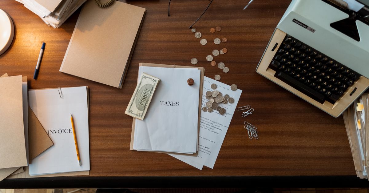Retro office scene featuring a typewriter, coins, documents, and stationary on a wooden desk.