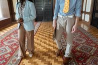 Man in Blue Button Up Long Sleeve Shirt and Gray Pants Standing Beside Woman in Brown