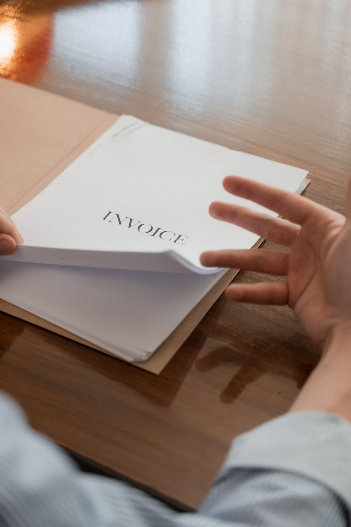 Person reviewing household invoice and utility expenses at table