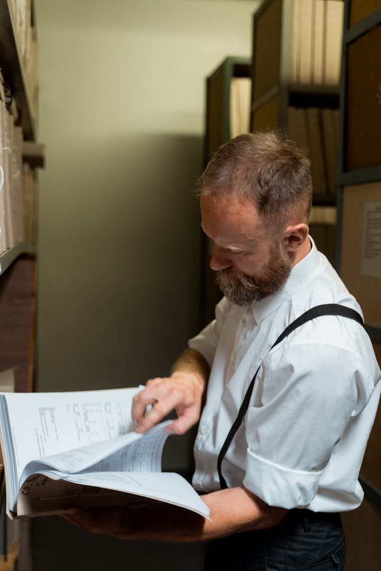 A Man Reading Documents In A Folder