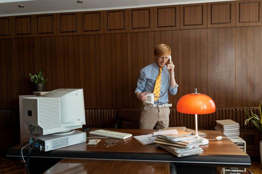 Caucasian man in a vintage office making a phone call at a desk with classic decor.