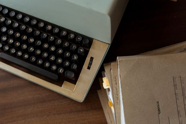 Vintage typewriter beside a stack of brown paper documents — MART PRODUCTION on Pexels