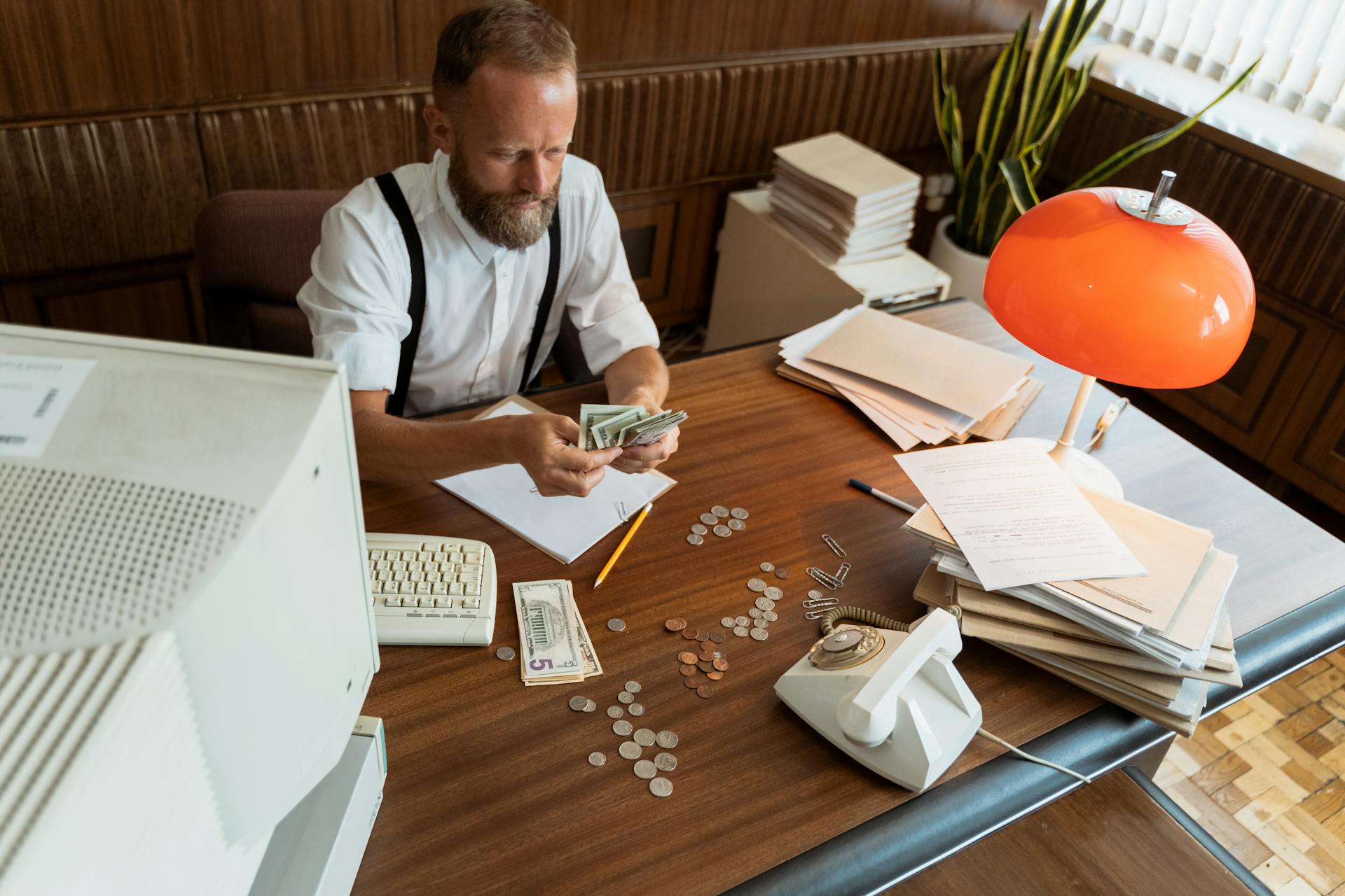 Photo of a Man in a White Shirt Counting Dollar Bills