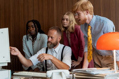 Free Vintage-style office meeting with diverse team examining computer screen. Stock Photo
