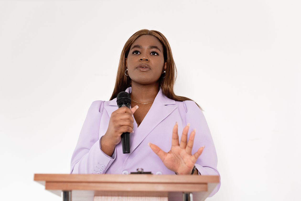 Confident woman speaking at a podium with a microphone, representing Eileen Wilder's journey from struggle to online income
