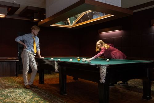 Free Two adults playing billiards in a stylish indoor setting. Stock Photo
