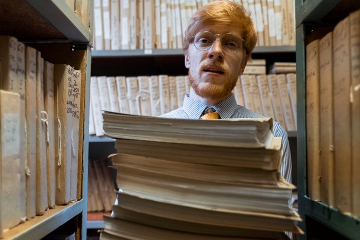 Archivist reviewing a stack of documents in a records room