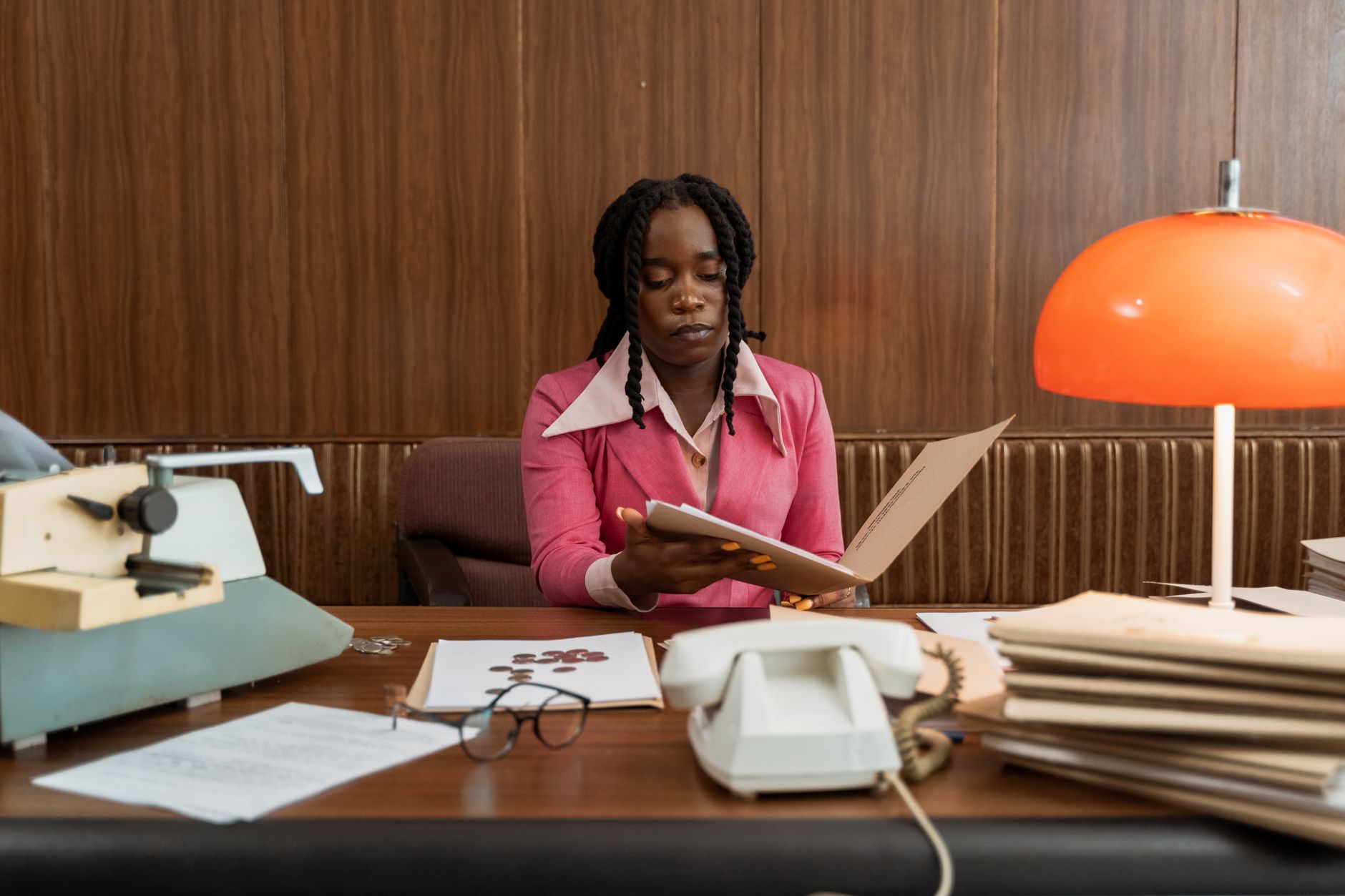 Businesswoman in vintage office setting with documents and typewriter, highlighting retro style.