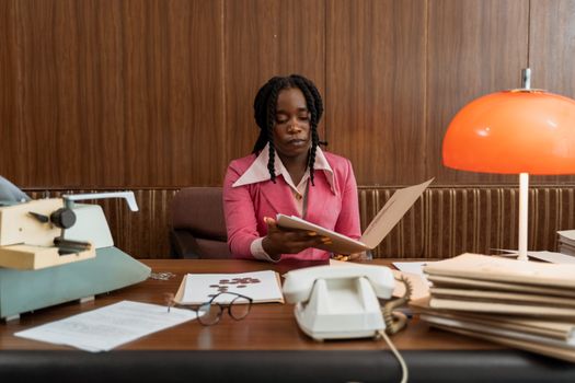 Businesswoman in vintage office setting with documents and typewriter, highlighting retro style.