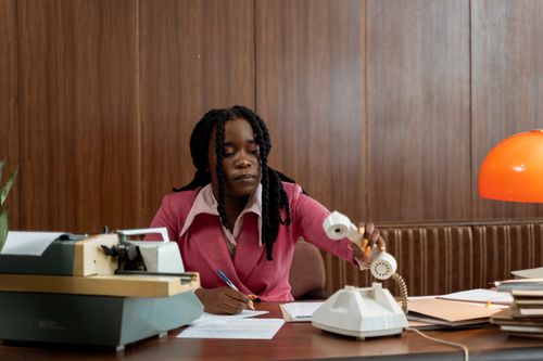 Free An adult woman in a vintage office setting, handling a rotary phone. Stock Photo
