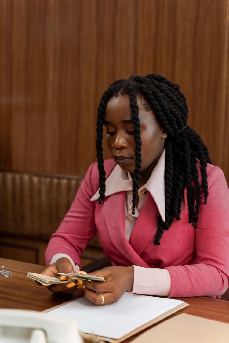 A Woman In A Pink Blazer Counting Money