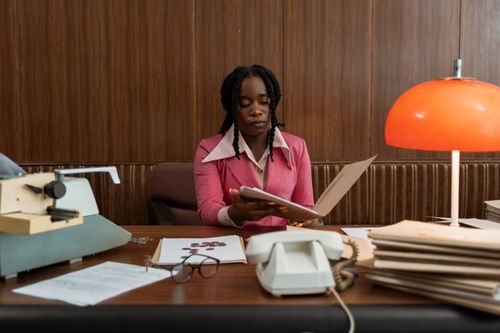 Free A professional African American woman working with files at a vintage desk setting in an office. Stock Photo