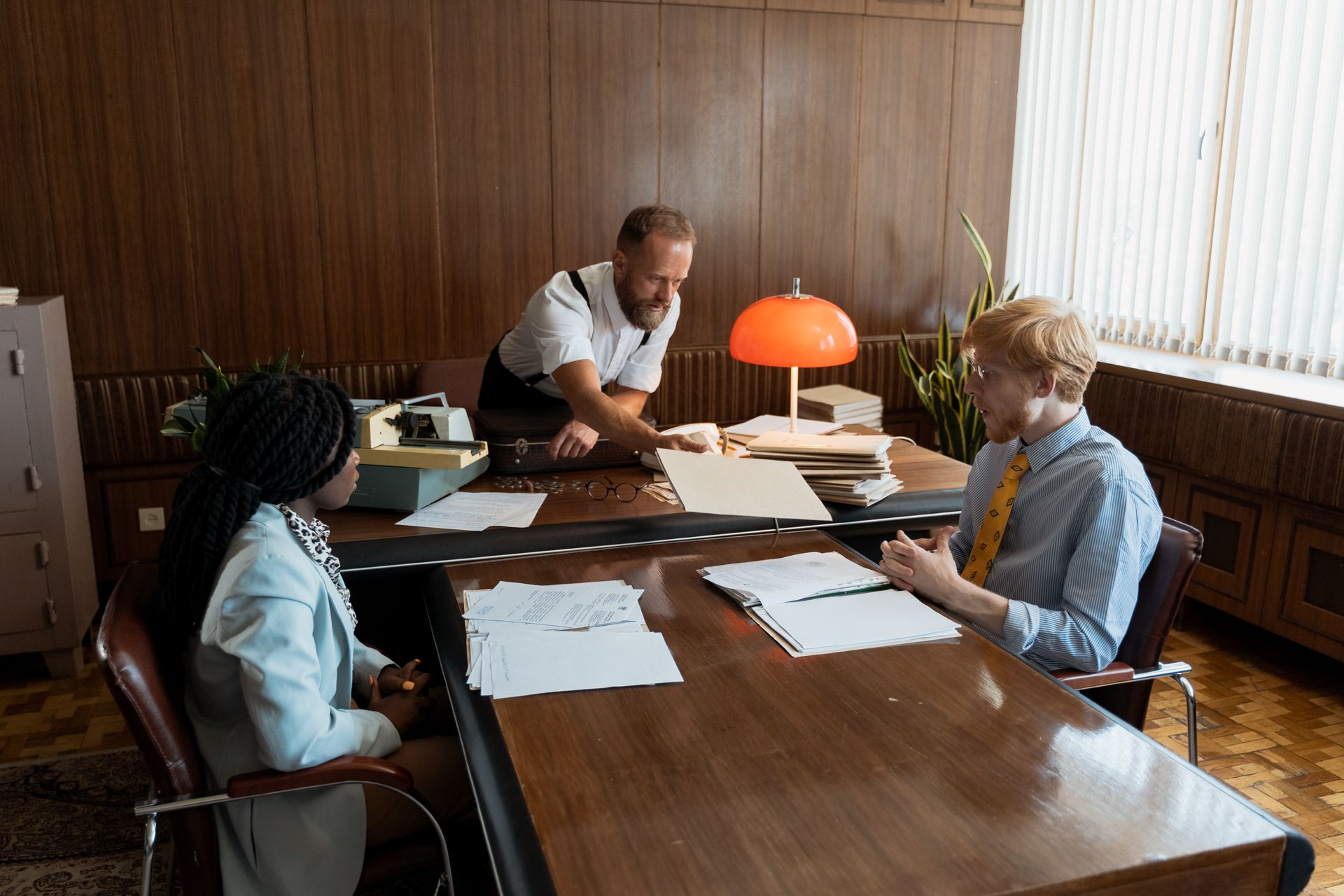 Retro office meeting with diverse team discussing documents. Mid-century style.