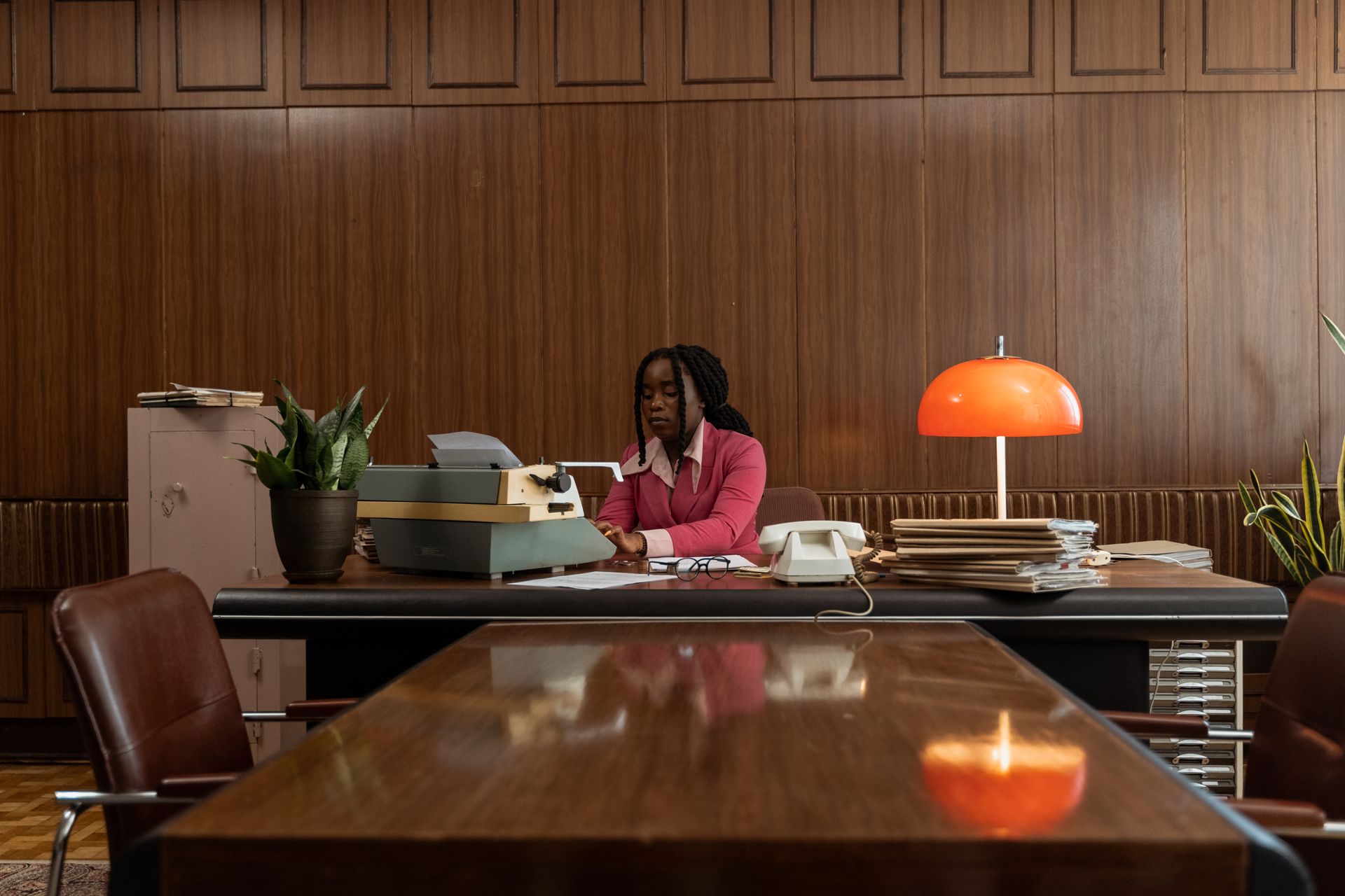 African American woman typing on an antique typewriter in a vintage office setting.
