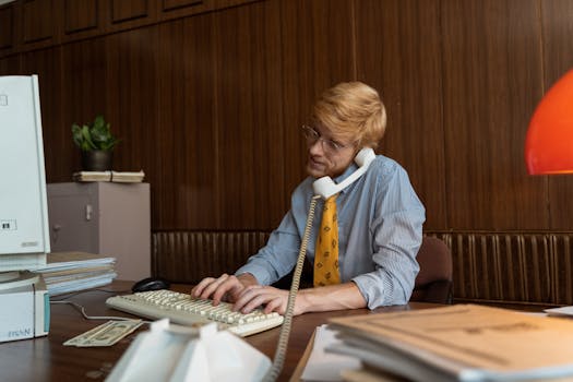 Vintage scene of a businessman on a corded phone at a retro office desk with classic documents.
