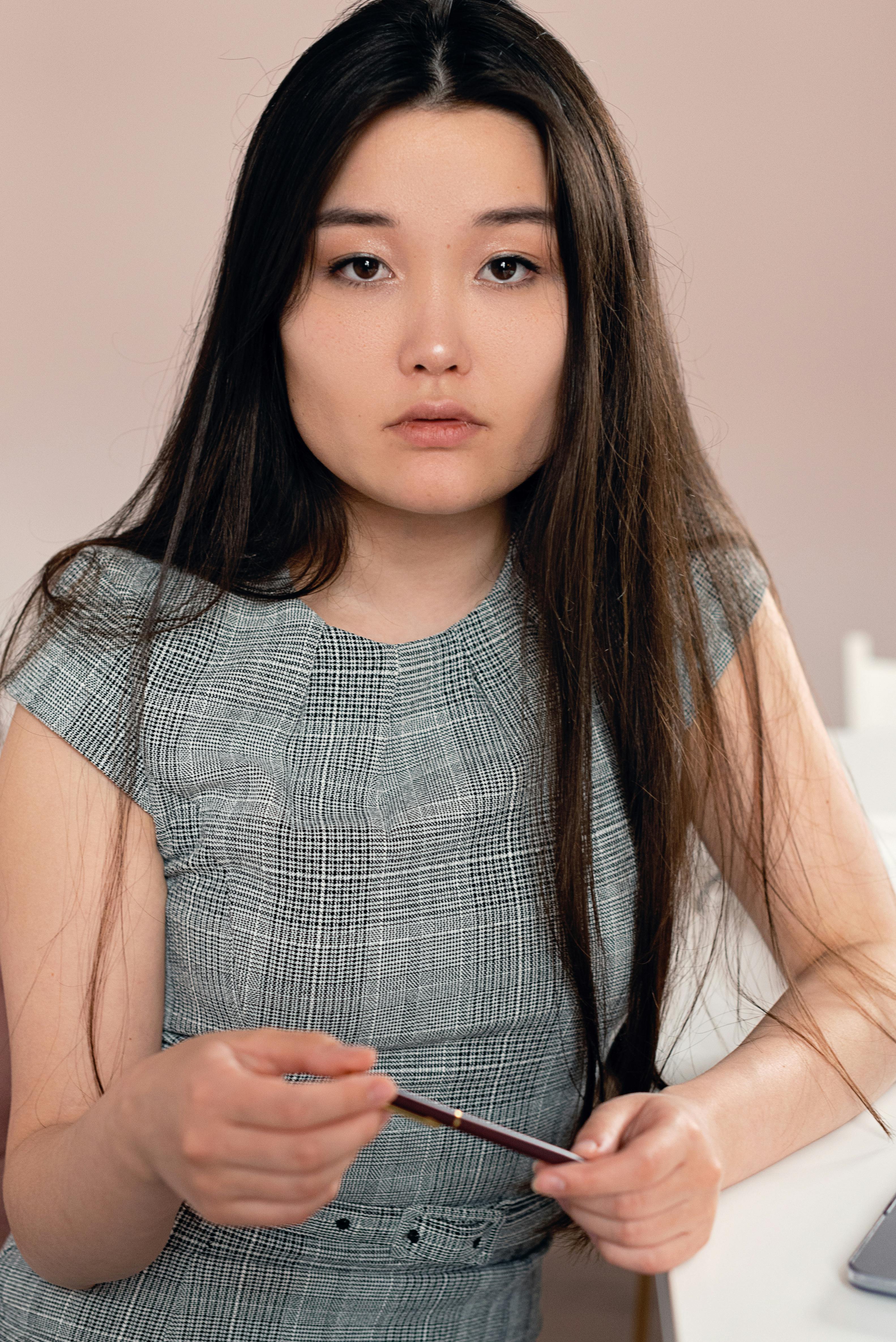 Portrait of a woman holding a pen, thoughtful indoors setting.