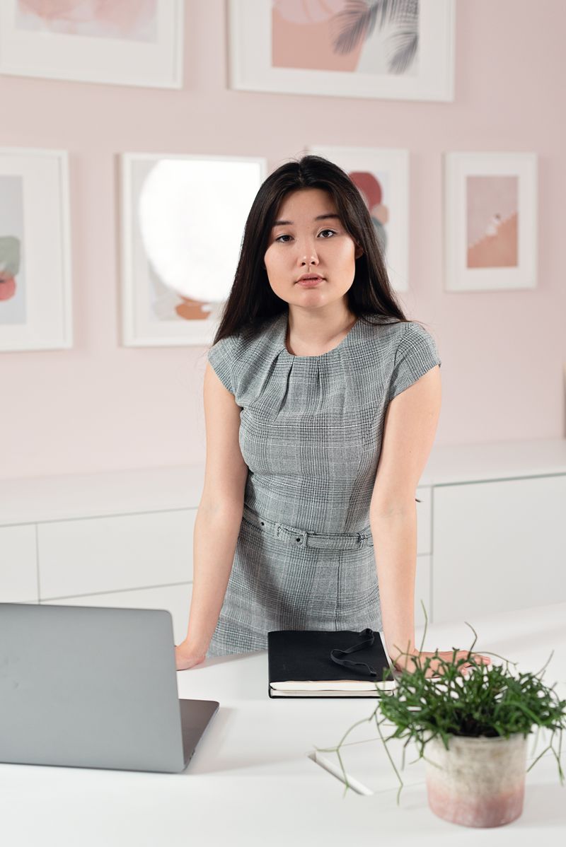 Professional businesswoman in a grey dress by her desk