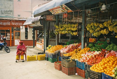 A Person Sitting Outside a Fruit Stand
