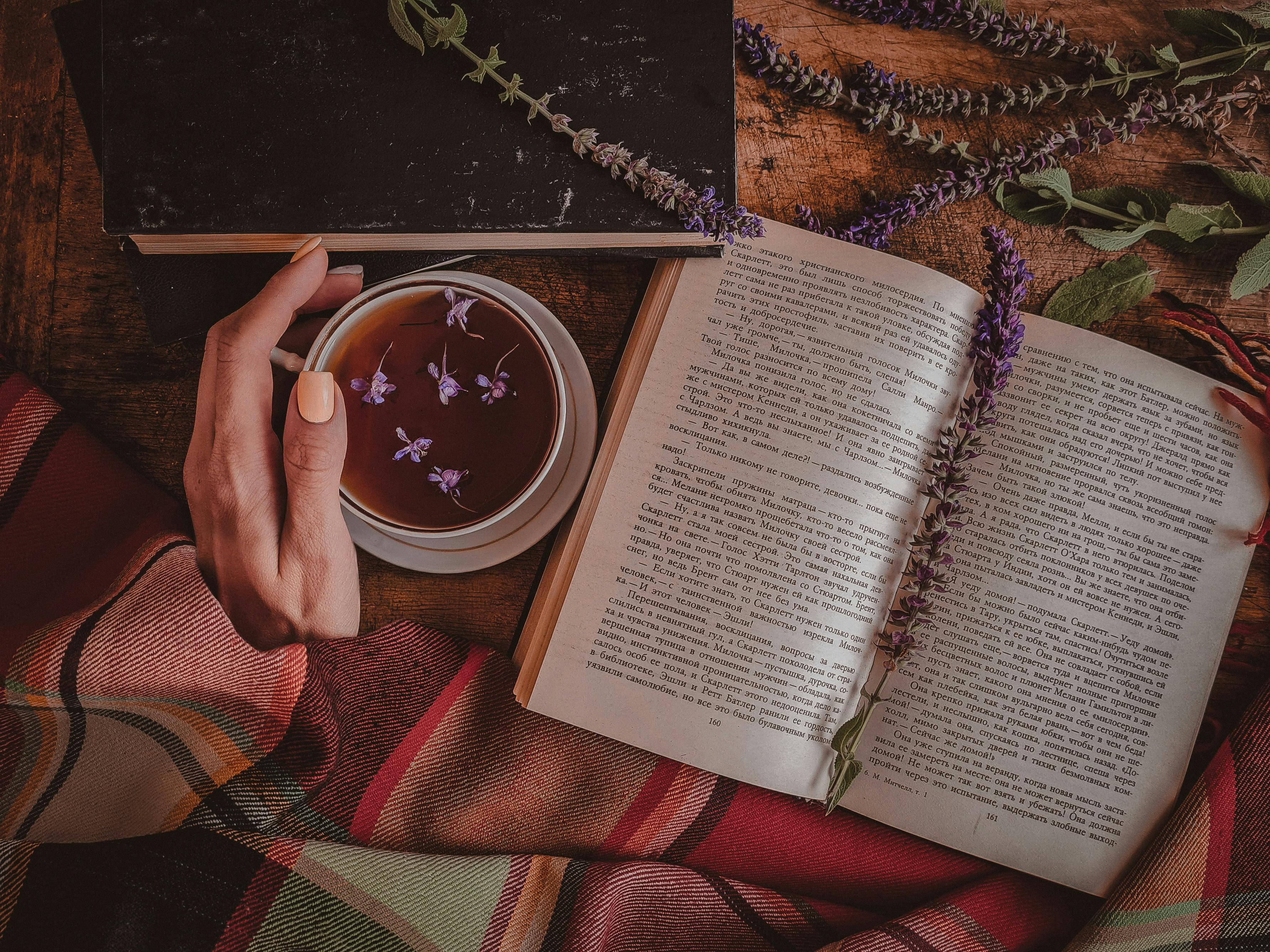 Warm and inviting setup with a cup of tea, open book, and flowers, perfect for a relaxing reading session.