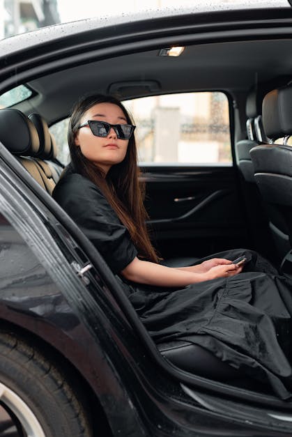 A Woman in Black Dress Wearing Black Framed Sunglasses Sitting in a Car ...