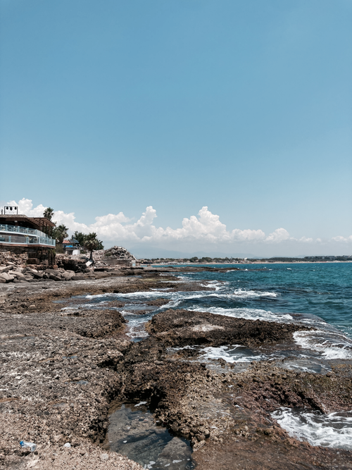 Free Explore the serene beauty of a rocky coastline meeting the vast ocean under a clear blue sky. Stock Photo