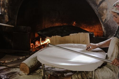 Free A baker prepares dough by an open fire in a traditional rustic setting, showcasing artisanal baking techniques. Stock Photo