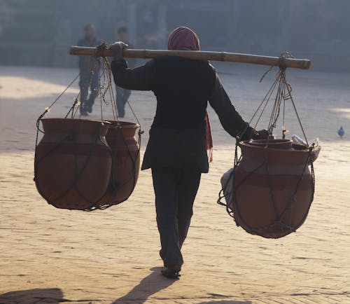 Person Carrying Pots Suspended on a Carrying Pole 