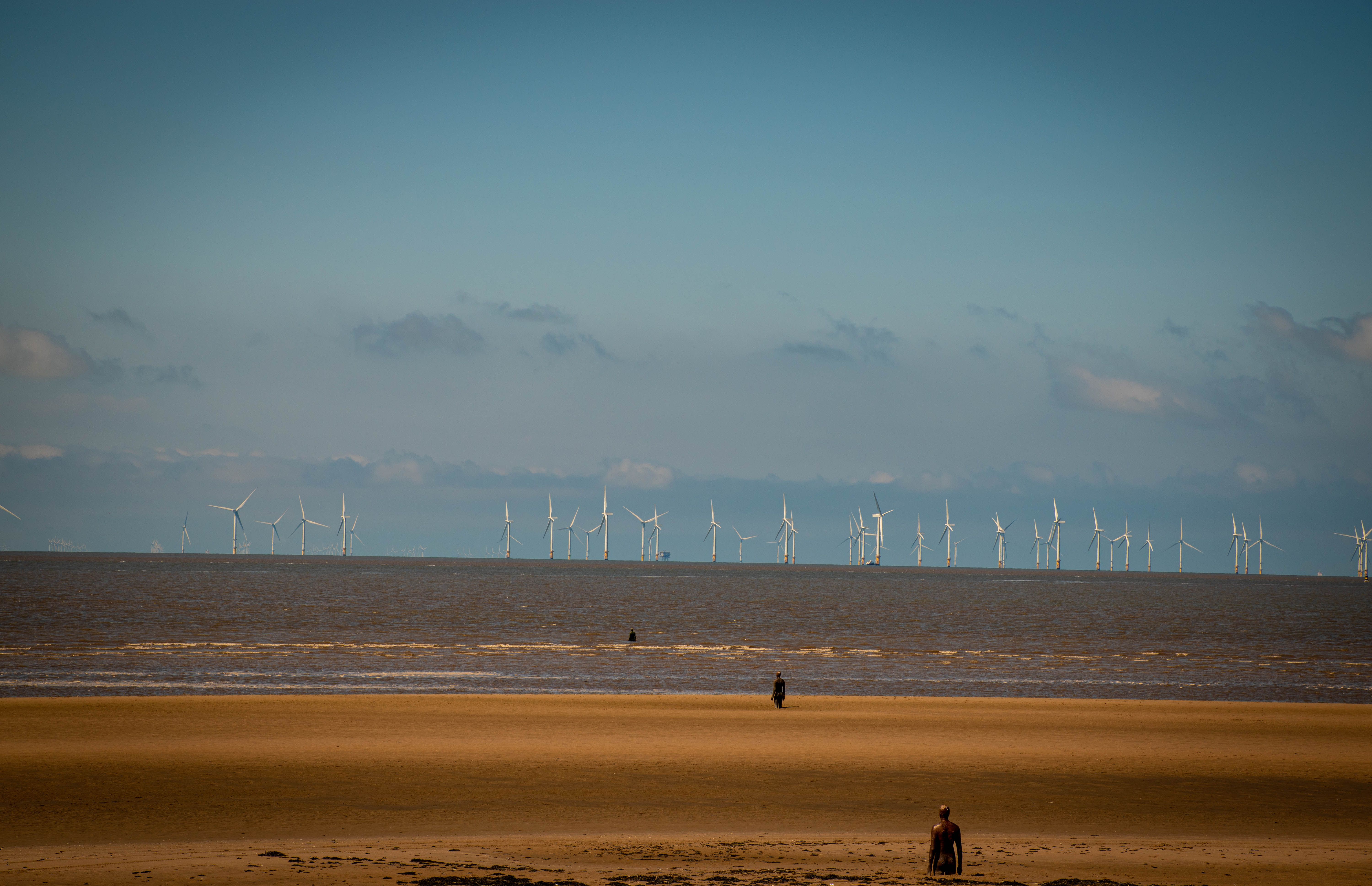 Scenic view of Crosby Beach with wind turbines and sculptures in Liverpool, England.