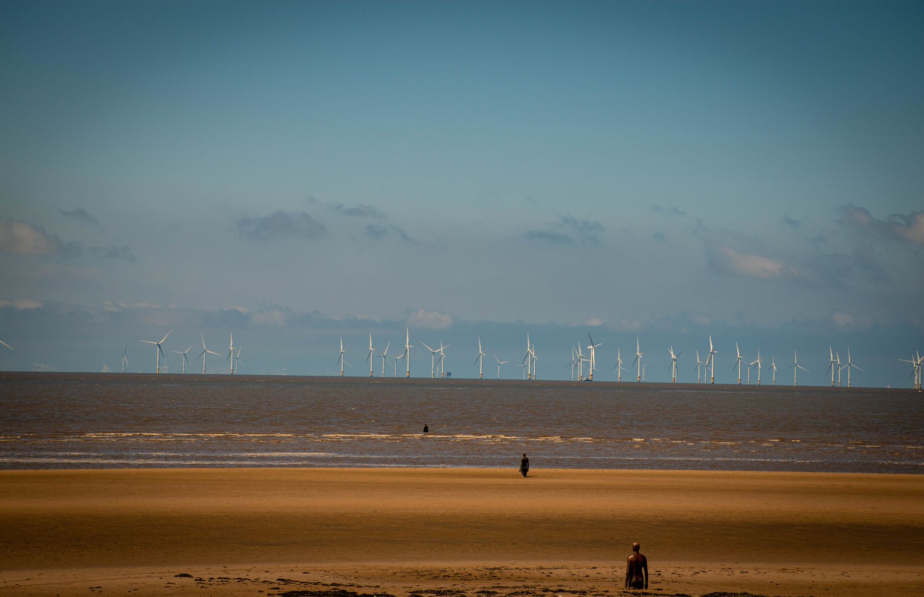 Scenic view of Crosby Beach with wind turbines and sculptures in Liverpool, England.