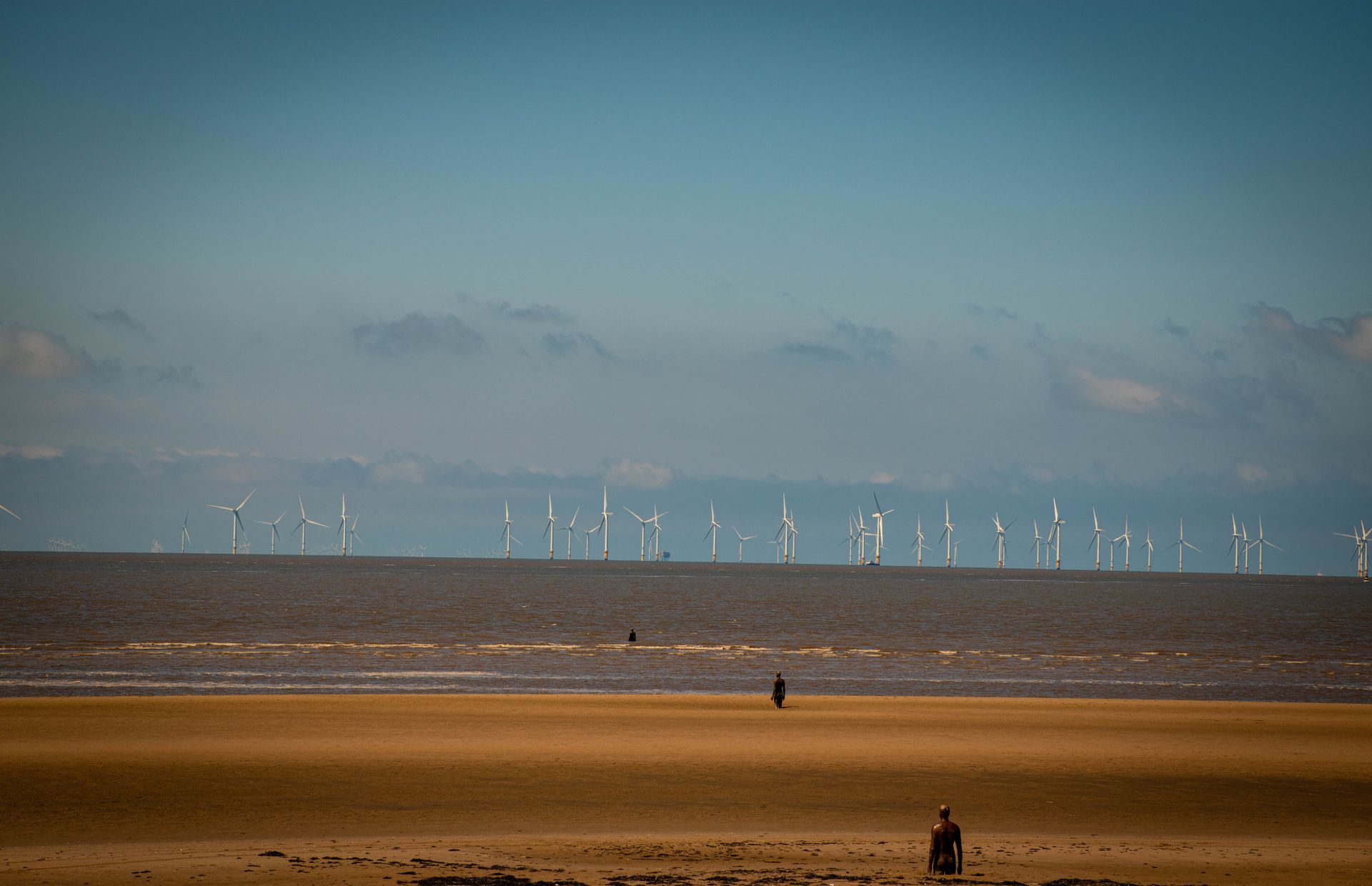 Scenic view of Crosby Beach with wind turbines and sculptures in Liverpool, England.