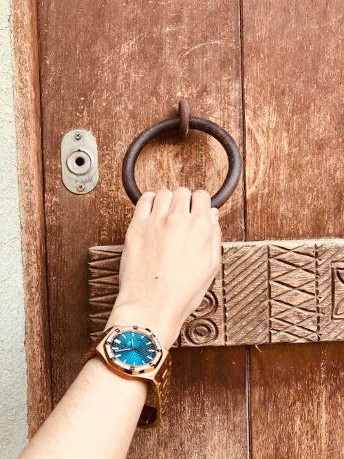 Person Knocks Using an Old Iron Ring Knocker on Wooden Door