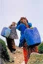Two People Carrying Blue Plastic Containers