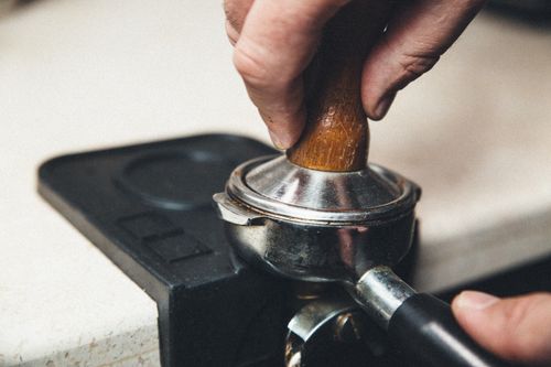 Free Detailed view of a barista using a tamper on a portafilter for espresso preparation. Stock Photo