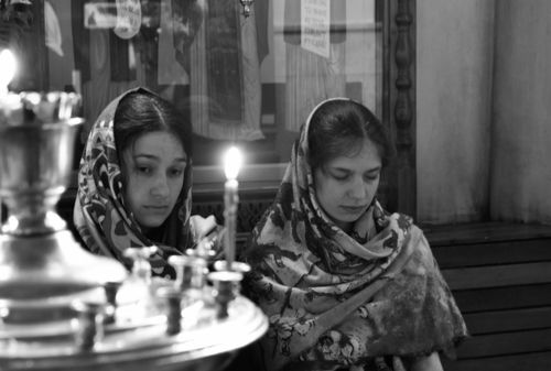 Free Two women in headscarves sit in introspection by candlelight indoors. Stock Photo