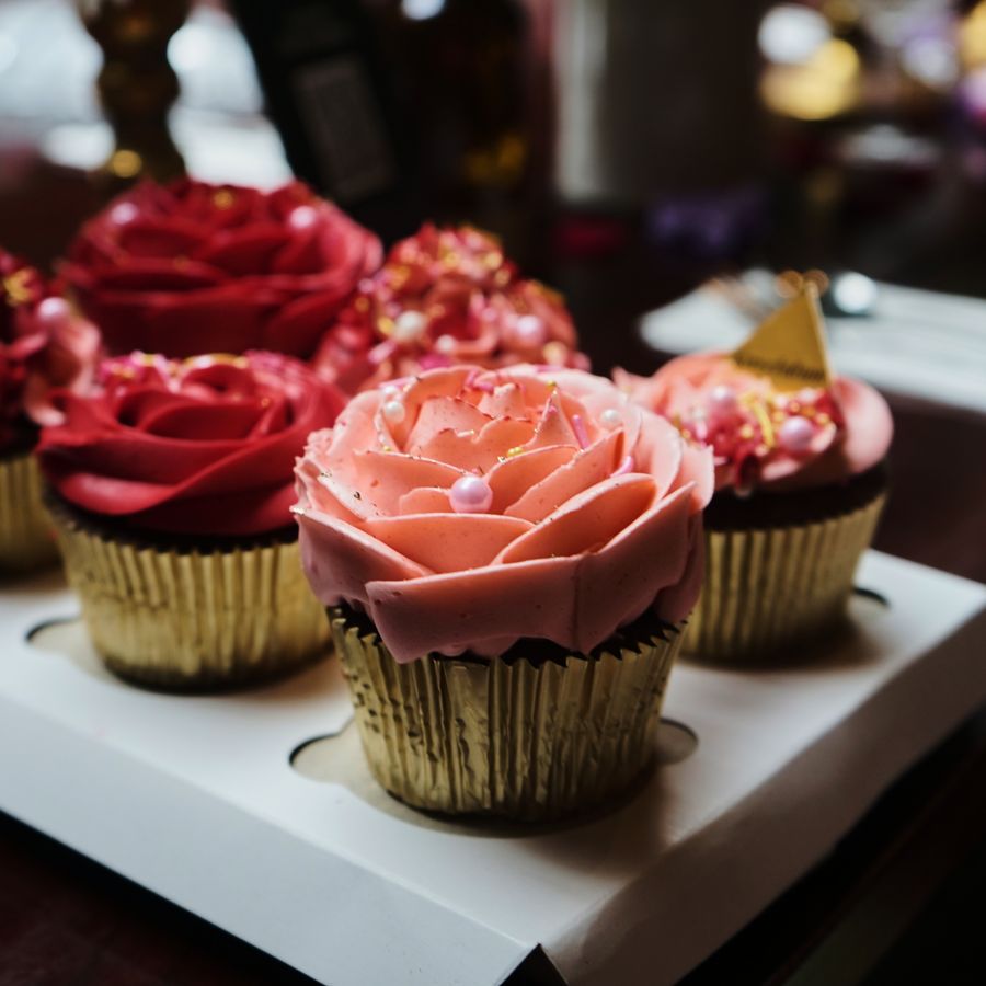 Rose-piped cupcakes in gold wrappers